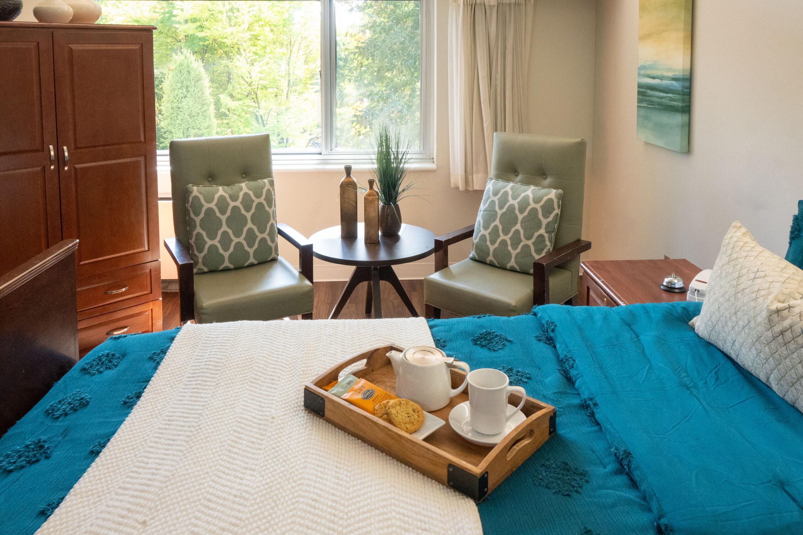 A housekeeping tray with tea and cookies sits on top of a bed in a Holladay Park Plaza residence.