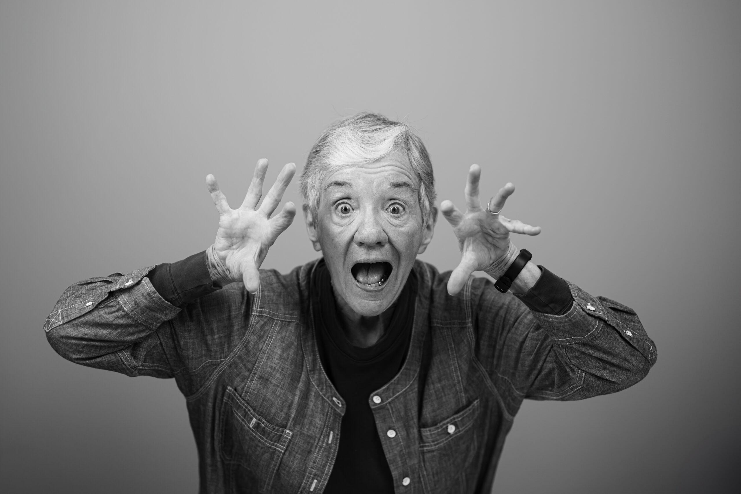 Black and white portrait of a Holladay Park Plaza resident with their hands next to their face, reaching outward.