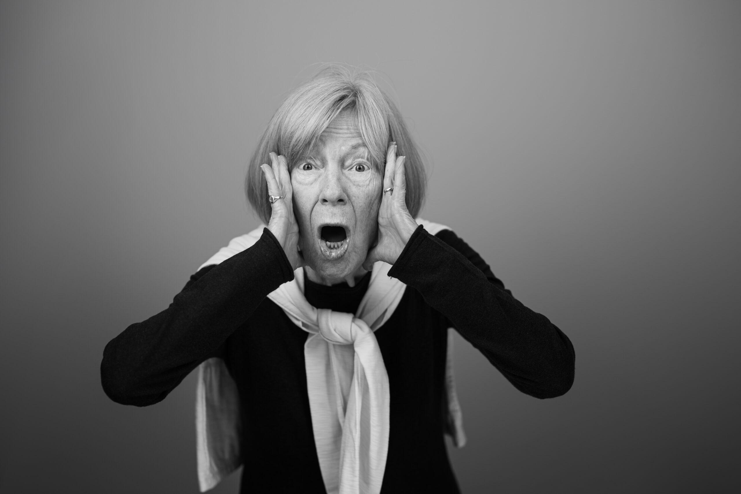 Black and white portrait of a Holladay Park Plaza resident with her hands on her face in a surprised expression.