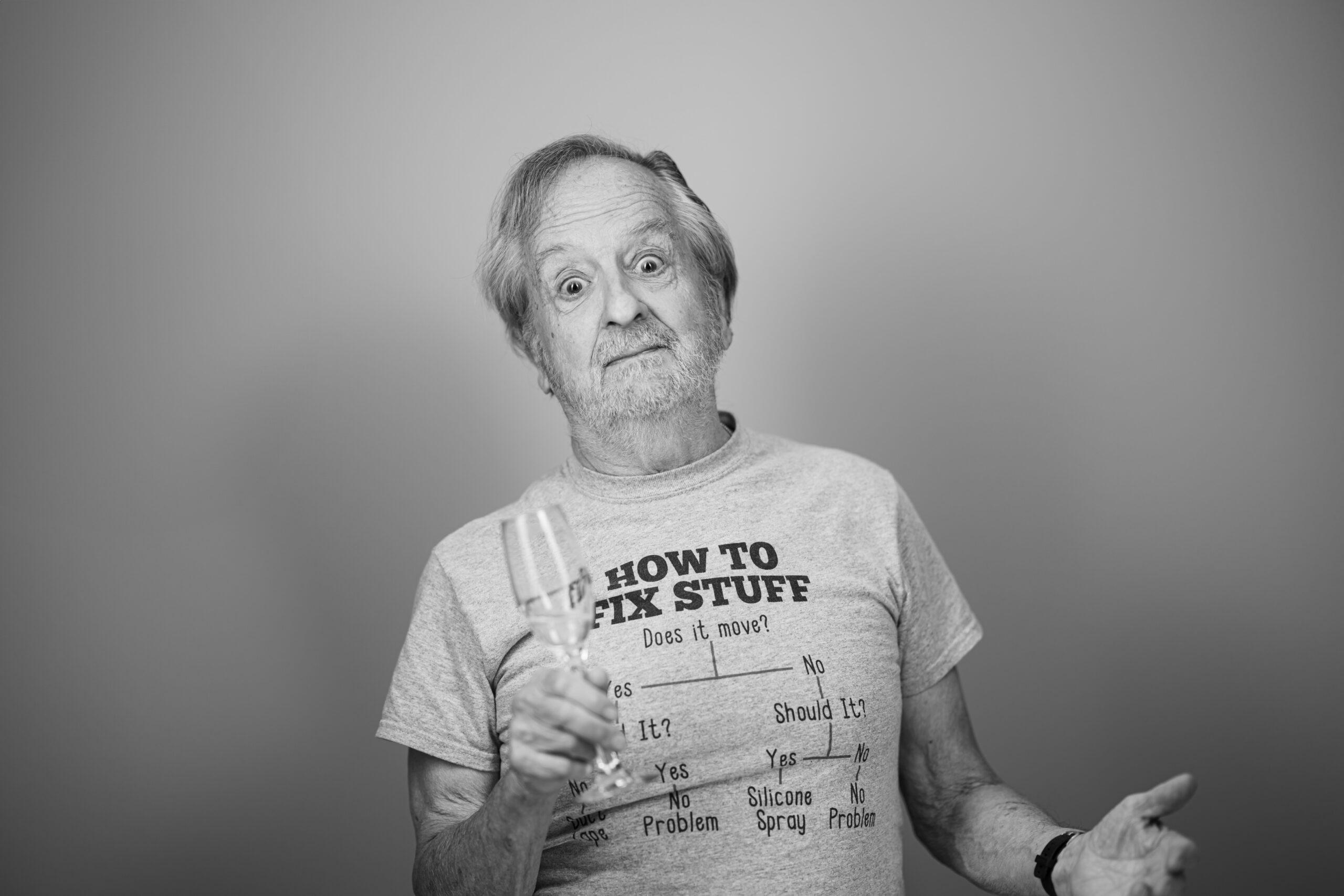 Black and white portrait of a Holladay Park Plaza resident holding a glass of champagne and making a silly face.