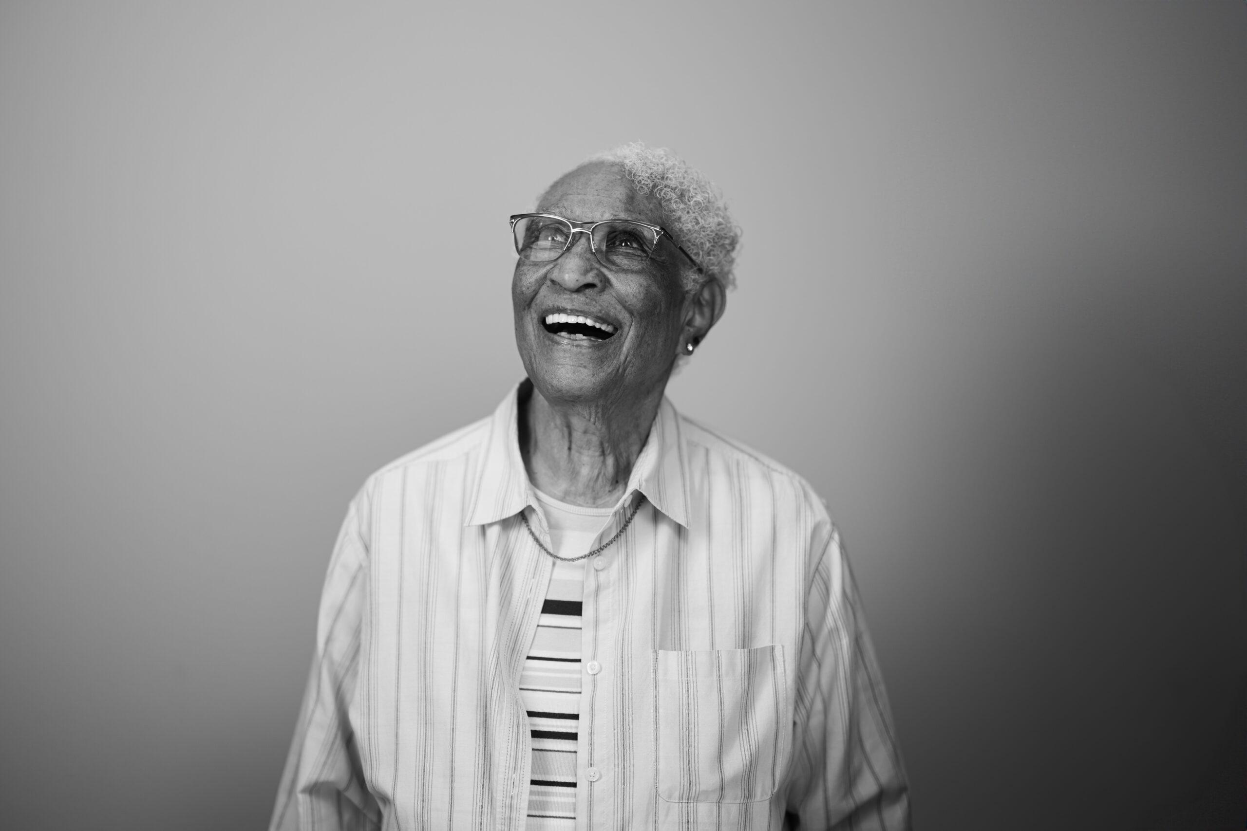 Black and white portrait of a Holladay Park Plaza resident smiling and looking away from the camera.