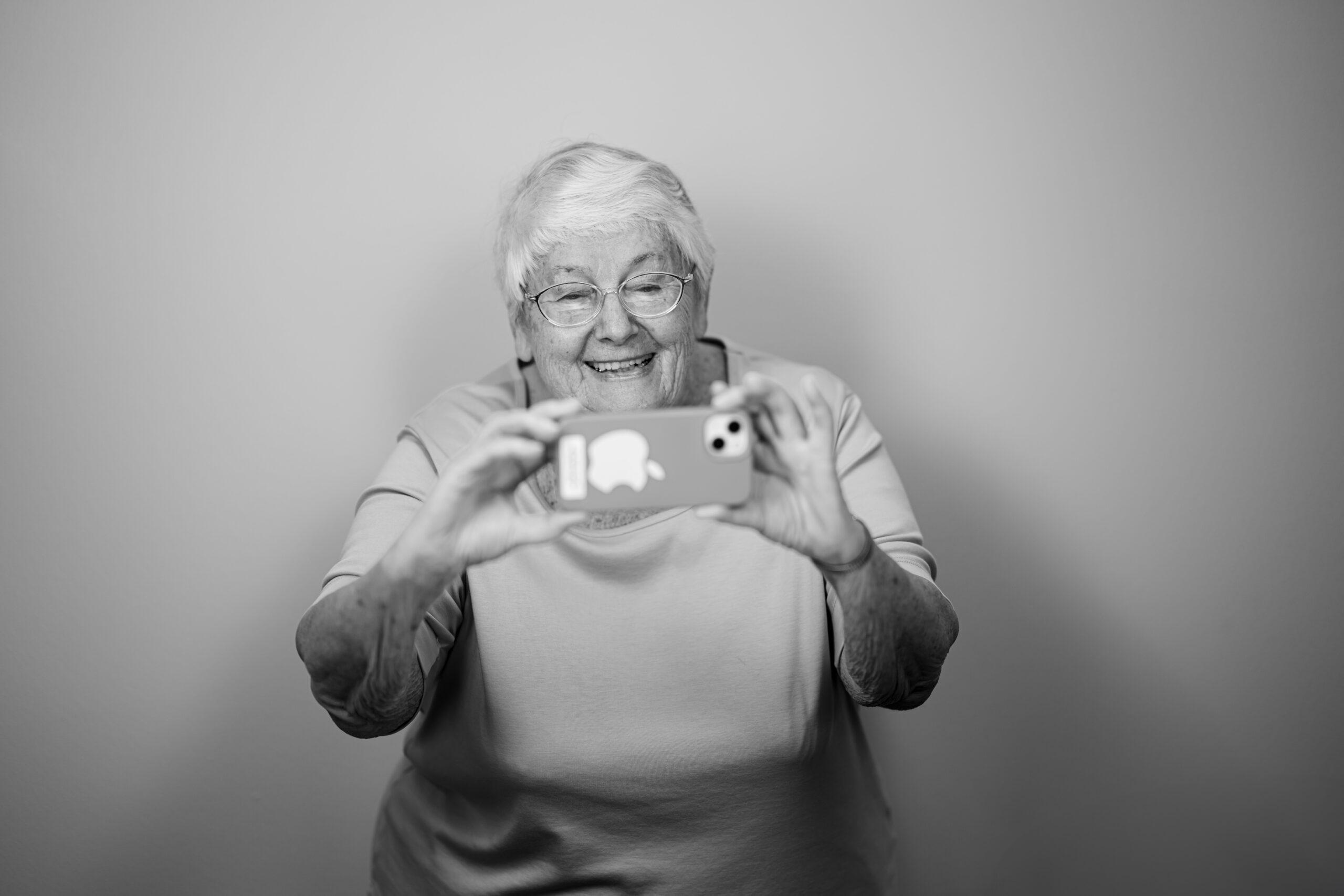 Black and white portrait of a Holladay Park Plaza resident smiling and taking a selfie.