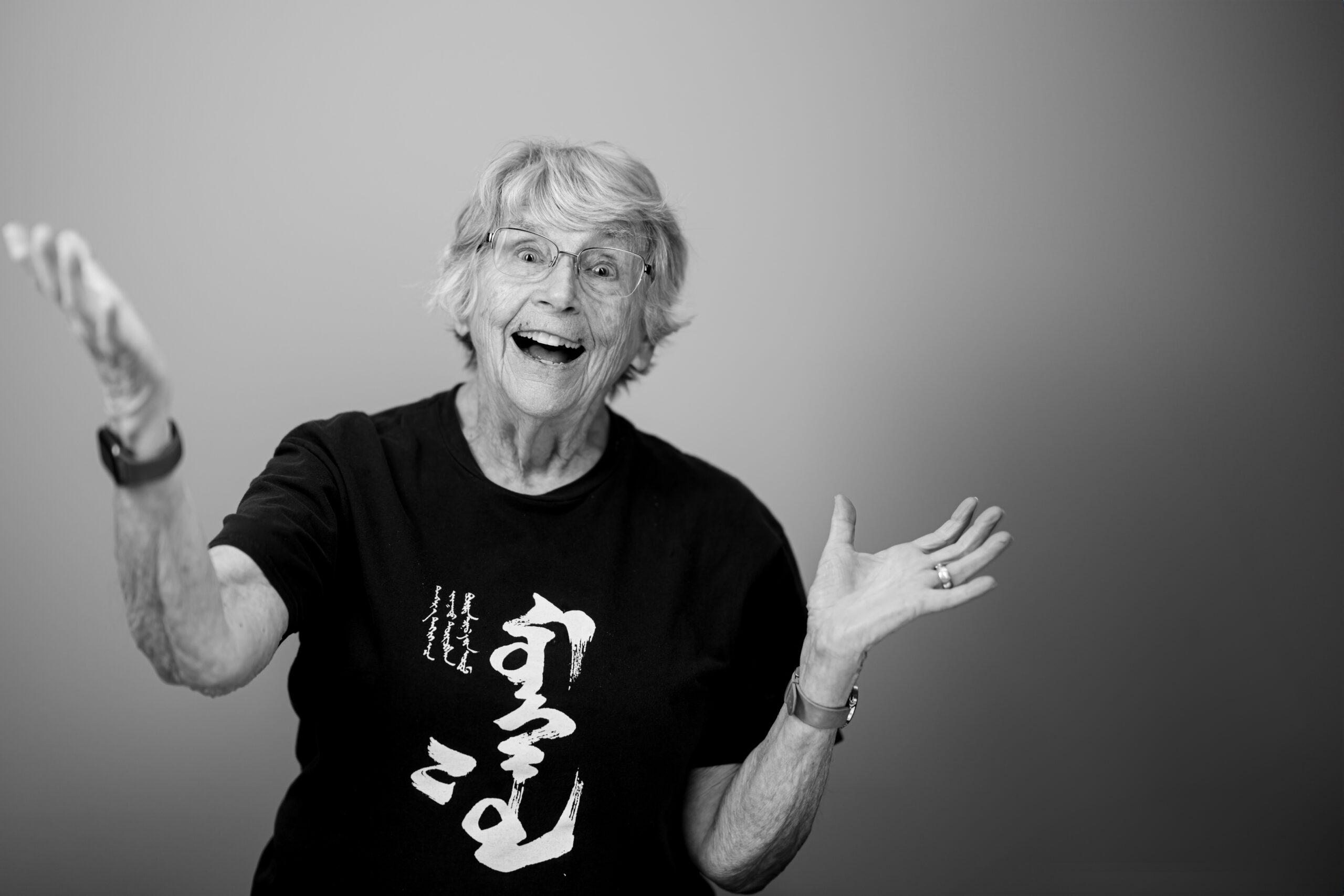 Black and white portrait of a Holladay Park Plaza resident with their hands up in an excited gesture.