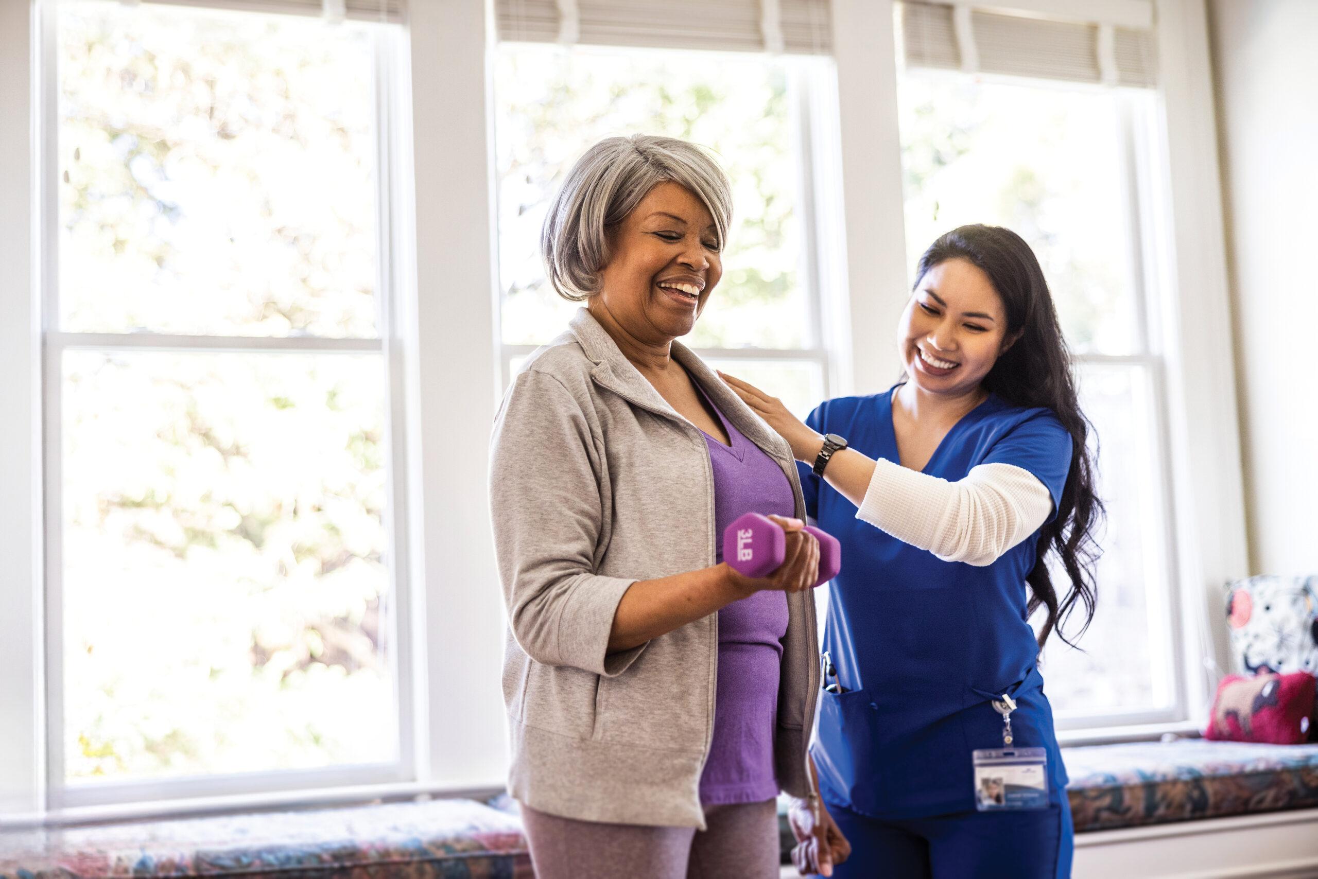 At home nurse helping a senior woman with physical therapy at home.