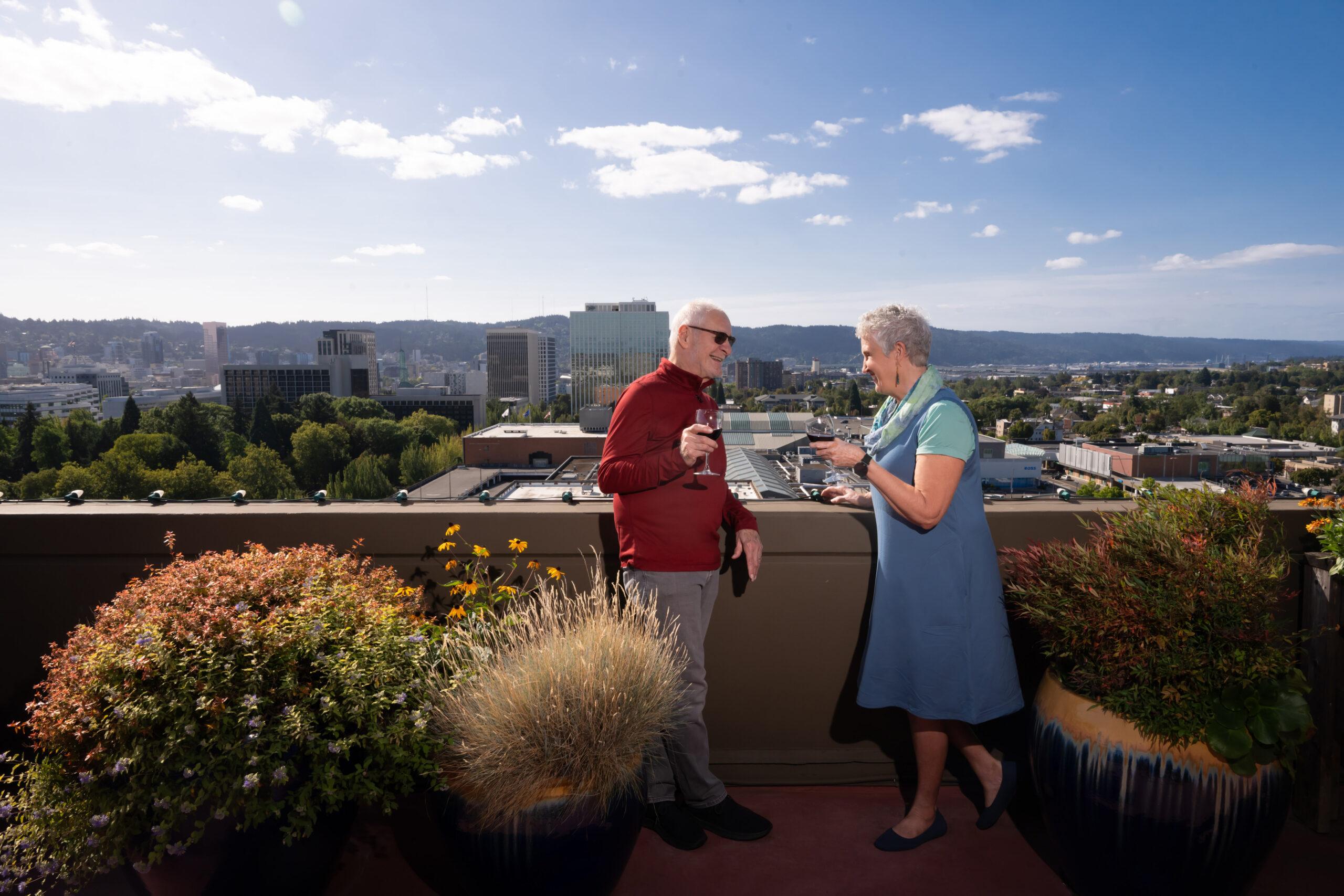 Holladay Park Plaza residents socialize with glasses of wine on a rooftop patio.