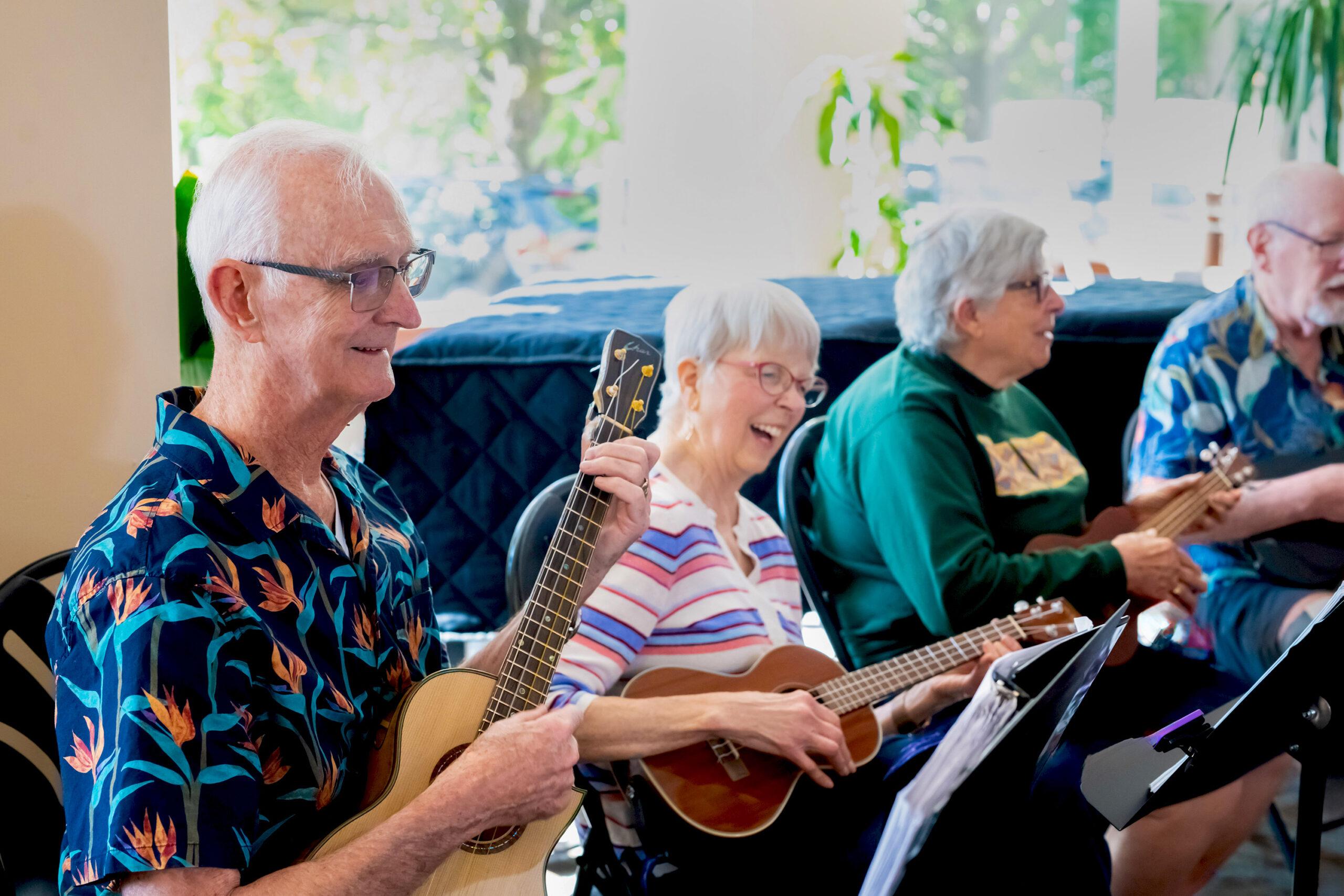 The Holladay Park Plaza Ukulele Club smiles as they rehearse.