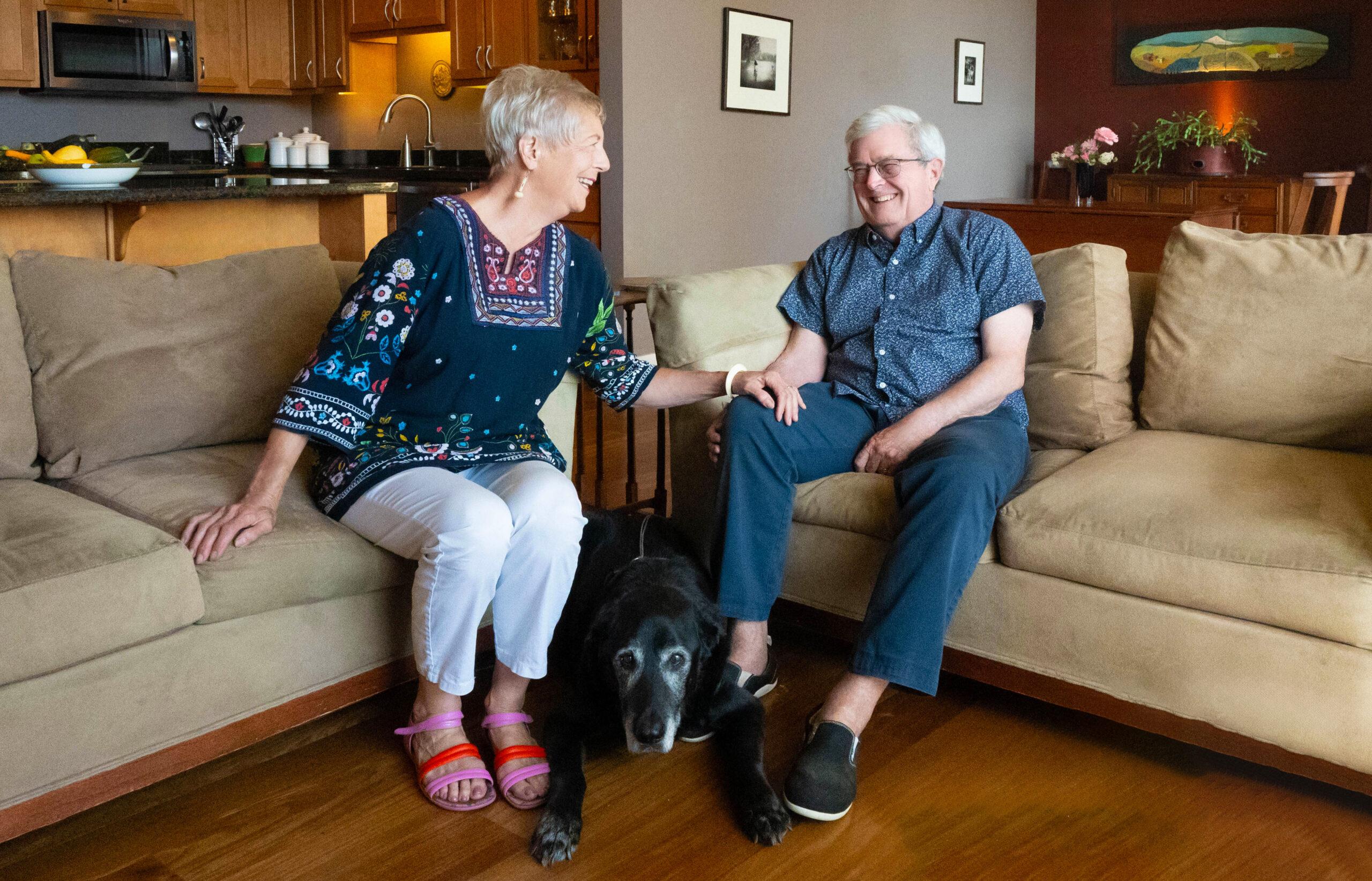 A couple laughs together in their apartment with their dog at Holladay Park Plaza.