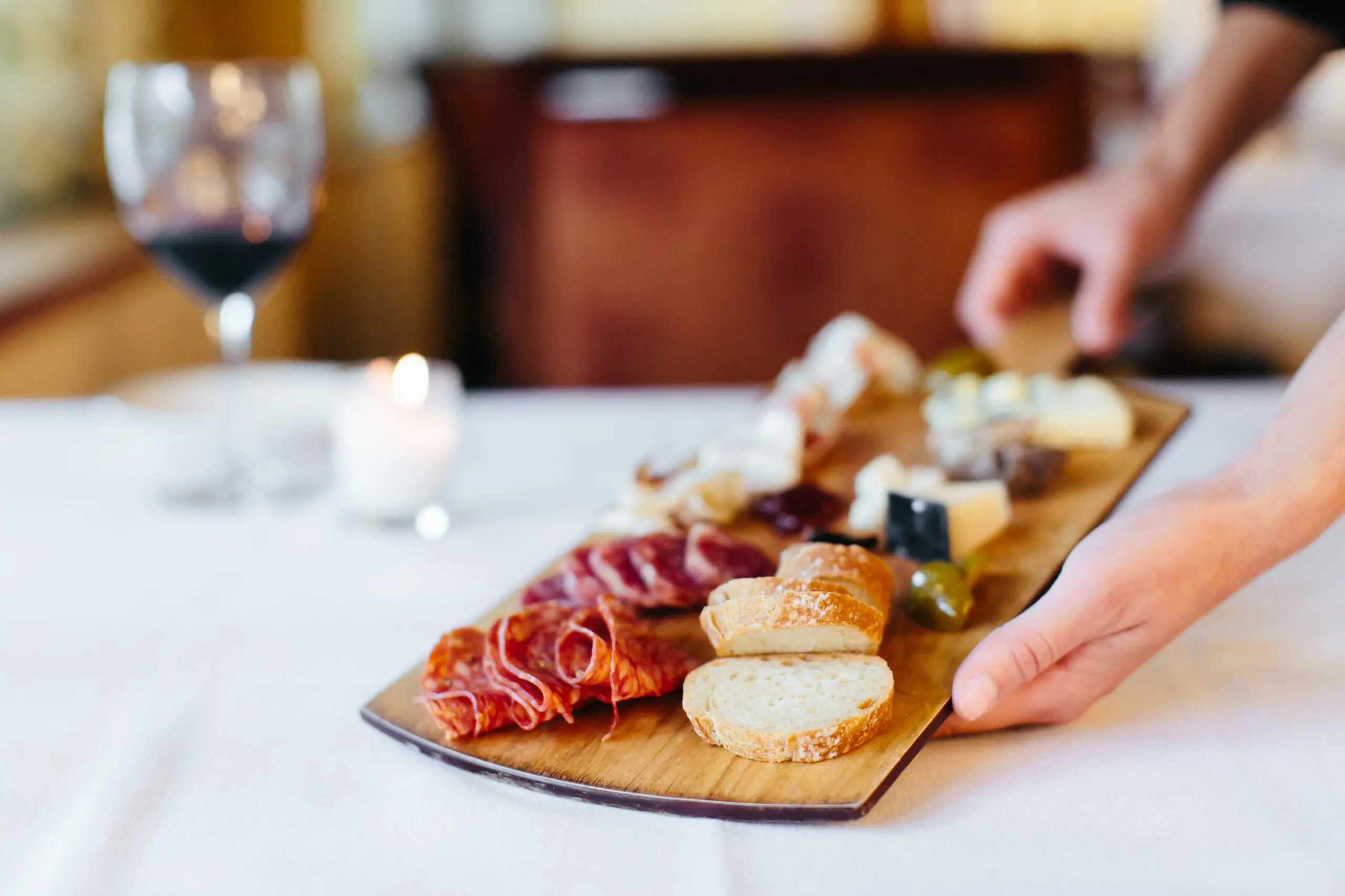 A gourmet charcuterie board on a white tablecloth.
